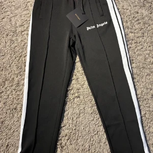 Palm Angels svarta trackpants med vit stripe - Helt nya palm angels byxor så gott som oanvända och tagen finns kvar och sitter på. Pris kan diskuteras 