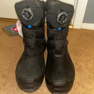 Svarta skyddsskängor från Base Protection - OBS priset går att diskutera.  Svarta boots från Base Protection med BOA-snörning och robust platt sula. Insidan är fodrad med grått meshmaterial för extra komfort och värme. Yttermaterialet är slitstarkt syntet och skinn, perfekt för kalla vinterdagar. Snygga detaljer i blått och reflekterande inslag på sidan. 