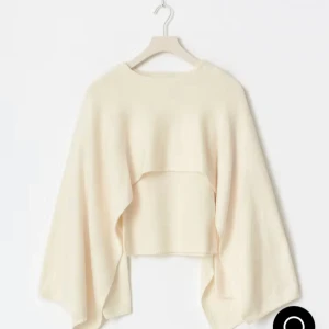 Knitted cape top  - Säljer en vit/creme stickad ”cape” tröja från Gina Tricot med coolt lager-på-lager utseende. Tröjan har breda, svepande ärmar och croppad passform som ger en unik siluett. Perfekt för dig som gillar trendiga och annorlunda plagg. Den är helt ny med prislapp på. Färgen står som vit på hemsidan.