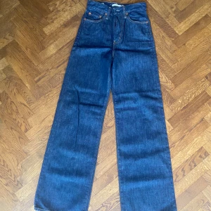 Levi's Ribcage Wide Leg jeans blå - Säljer ett par Levi's Ribcage Wide Leg jeans i mörkblå denim. Stl 25/32. Aldrig använda eller tvättade. Byxorna har hög midja, raka och breda ben samt klassiska fem fickor och knappgylf. Snygga kontrastsömmar och Levi's Premium-märke på insidan. 