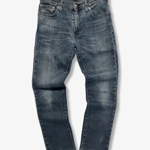 Levi's 511 slim fit - Säljer pågrund av att dem att inte passade mig. Snygga Levi's 511 jeans i en tvättad blå färg med klassisk femficksdesign. Jeansen har en smal passform och raka ben, perfekt för en stilren look. Tillverkade i slitstarkt denim med subtila slitningar för en cool vibe.