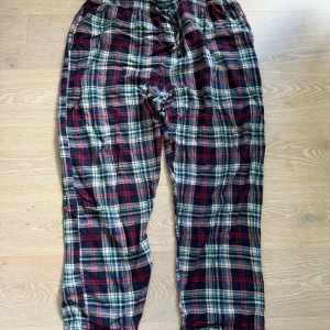 Rutig byxa från Ralph Lauren XL - Riktigt sköna byxor från Ralph Lauren i klassiskt rutig design med blå, röd, grön och vit färg. Tillverkade i 100% bomull med elastisk midja och avslappnad passform. Perfekta för chill dagar hemma eller när du vill vara bekväm.