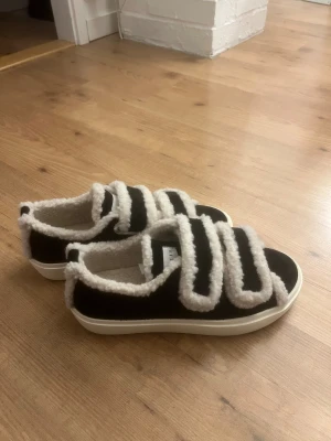 Svarta sneakers från Inuikii med teddy - Säljer mina populärara svarta sneakers från Inuikii med fluffiga vita teddy-detaljer och breda kardborreband. Skorna har rund tå, platt vit sula och är fodrade med mjukt teddy-material. Perfekt nu till vintern💕❄️ skorna är inte använda och leveranskartongen finns med och skickas i den💕