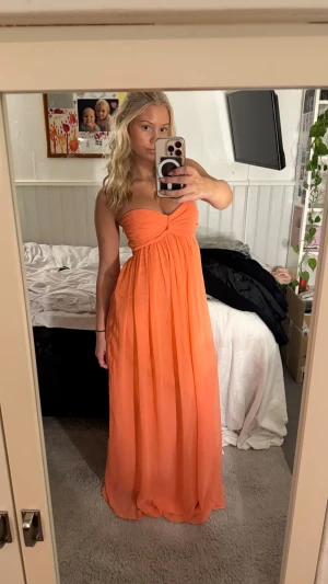 Rosa/korall balklänning - Jättefin rosa/korall balklänning från Nelly i storlek S. Sitter jättefint på mig som är 165 cm lång och vanligtvis har storlek S. Den är väldigt lång så den släpar lite vilket är superfint! Och den har ett innerlager så inte alls genomskinlig!