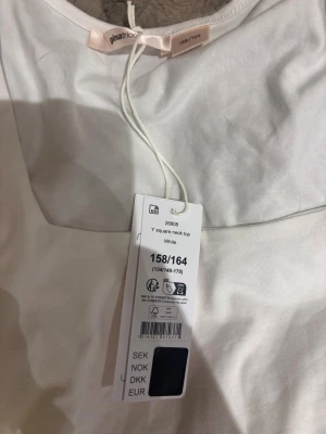 Vit långärmad topp från Gina Tricot - Säljer en stilren vit långärmad topp från Gina Tricot i storlek 158/164. Toppen har en fyrkantig halsringning som ger en modern vibe och är gjord i mjuk bomull. Perfekt att matcha med jeans eller kjol för en clean look.