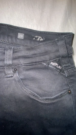 Replay Hyperflex svarta jeans, W29 L30 - Svarta Replay Hyperflex jeans med klassisk femficksdesign och stretchigt material som sitter skönt. Snygga detaljer som Replay-logga på fickan och metall-R vid bakfickan. Passar dig som gillar stilrena och bekväma jeans med modern känsla.