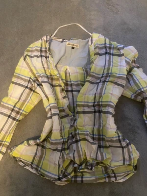 Rutig gul skjorta från Hampton Republic - Snygg rutig skjorta från Hampton Republic i storlek S. Skjortan har ett mönster i gult, vitt, grått och blått med långa ärmar och klassisk krage. Tillverkad i lätt och skön bomull, perfekt för dig som gillar färg och mönster. Passformen är normal och skjortan har knappar framtill.