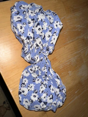 Blommig pannband från Morris Lady - Supersöt pannband från Morris Lady med vitt och svart blommönster. perfekt för dig som gillar en feminin och fräsch stil. 