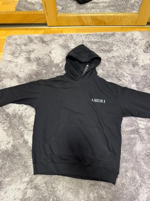AMIRI hoodie  - Svart hoodie från AMIRI med vit logga på bröstet och stort botaniskt tryck i grönt och vitt på ryggen. Tröjan har huva, känguruficka och långa ärmar. (PRIS KAN DISKUTERAS)