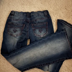 Blå bootcut jeans från Gina Tricot - Snygga blå bootcut jeans från Gina Tricot i storlek 164💓 Jeansen har röda kontrastsömmar,  och snygg broderad detalj på bakfickorna. Säljer för att de inte kommer till användning, är i nytt skick🤗 Ordinarie pris: 359