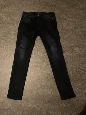 Replay Anbass svarta slim jeans W31/L32 - Säljer ett par svarta Replay Anbass jeans i slim fit. Klassisk femficksmodell med snygg tvätt och diskreta slitningar. Jeansen är tillverkade i stretchig bomullsblandning för skön passform och har dragkedjegylf. Perfekta till sneakers eller boots.