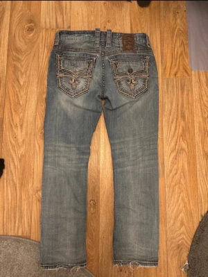 Rock revival jeans - Nice cool rock revival jeans in size 33 and in a straight fit. The only thing missing is one button on thr back pocket. Measurements (+/-1cm) Waist: 44cm Leg opening: 20cm Inseam: 78cm Outseam (waist and down): 103cm Thigh: 26cm