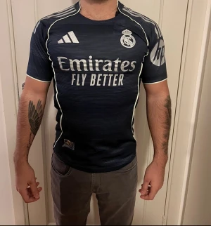 Real Madrid matchtröja 2023/24 - ⚪️Real Madrid - Bortatröja 2023/24.                          • Sponsor Emirates Fly Better                                        • Elegant mörkblå design med vita detaljer🤍💙