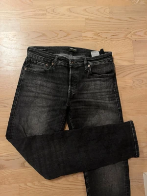 Svarta skinny jeans från Jack & Jones - Snygga svarta jeans från Jack & Jones med rak passform och klassisk femficksdesign. Jeansen har en mörk tvätt med lätt slitning och är gjorda i stretchigt denim för skön komfort. 