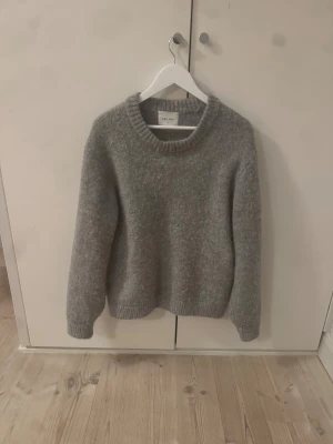 Grå stickad tröja från Vailent - Mysig grå stickad tröja från Vailent i storlek S. Tröjan har en rund halsringning och ribbade muddar vid ärmslut och nederkant. Perfekt för kyliga dagar och enkel att matcha med jeans eller kjol. Klassisk och stilren design som funkar året runt. Stor i storleken