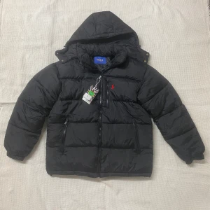 Svart pufferjacka från Polo Ralph Lauren - Aldrig använd inga hål eller fläckar eller annat tecken på användning. Perfekt nu inför vintern. Fraktar samma dag eller dagen efter. Såklart får man lite bättre pris vid snabb affär.