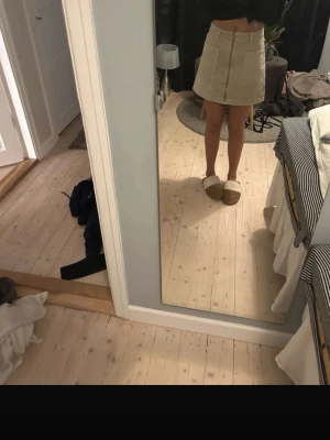 Beige kortkjol i jesns - Snygg beige kortkjol i jeans med klassisk rak passform och diskreta sömdetaljer. Kjolen har hög midja och passar perfekt till både stickade tröjor och t-shirts. Enkel att matcha och supertrendig för säsongen.