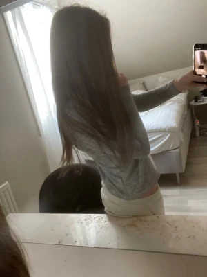 Grå ribbad kofta med knappar - Säljer en grå, ribbad kofta med långa ärmar och knäppning framtill. Koftan är figurnära och har en enkel, stilren design som passar perfekt till jeans eller kjol. Materialet känns mjukt och stretchigt.