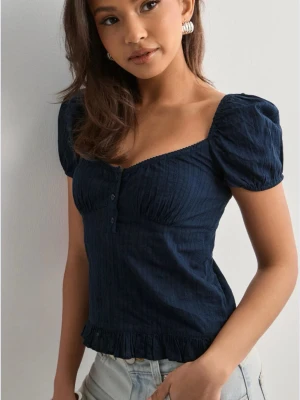 Mörkblå blus med puffärm och knappar - Supersöt mörkblå blus med puffärmar, knappar framtill och volangkant nedtill från Nelly. Blusen har en lätt croppad passform och en söt, feminin look med markerad byst. 