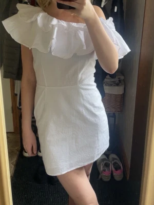 Vit klänning/student klänning - Säljer en vit kortklänning med offshoulder-design och stor volang runt axlarna. Perfekt som studentklänning!💕💕pris går att diskuteras!