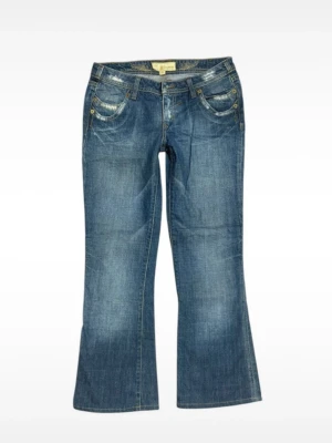 Blå bootcut jeans från Miss Sixty - Snygga blå bootcut jeans från Miss Sixty med slitningar och detaljerade fickor fram och bak. Klassisk femficksmodell med låg midja och guldfärgade nitar. Tillverkade i mjuk denim som sitter skönt hela dagen.