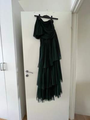 Mörkgrön balklänning  - Jättefin balklänning i mörkgrön. Klänningen är i tyll och använt en gång. Den är uppsydd så den passar mig som är 154 cm lång. Klänningen har en liten reva i tyget nedtill (bild 3 och 4) men det syns inte eftersom att det är tyll. Använd en gång.🩷 modellen finns inte kvar och nypris ligger på ca 1500 kr. 