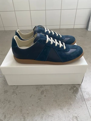Maison Margiela sneakers – helt nya – strl 42 - Säljer ett par Maison Margiela sneakers. Skorna är helt nya och oanvända, kommer med originalkartong och dust bag.  Jag har tyvärr ingen djupare kunskap om Maison Margiela och kan därför inte garantera äkthet, säljs som helt nya.Pris går att diskutera vid snabb affär.   Mitt pris: 2199 kr Nypris: ca 6499 kr  Vänliga hälsningar, Stylespotresell