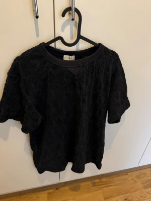 Snygg och unik frottétopp - Snygg kortärmad topp i mjuk frotté med diskret strukturmönster. Rund halsringning med ribbad kant och avslappnad passform. Perfekt för en chill och trendig look.