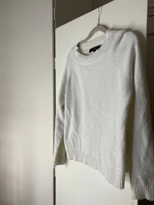Vit stickad tröja från Vero Moda - Mysig vit stickad tröja från Vero Moda med rund halsringning och ribbade muddar vid ärmslut och nederkant. Perfekt för lager-på-lager och enkel att matcha med jeans eller kjol. I köpet ingår en oanvänd washing bag för att kunna skydda dina kläder vid tvätt! 