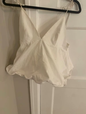 Vit linnetopp från Zara med smala band - Supersnygg vit linnetopp från Zara med smala axelband och v-ringad hals. Toppen har en luftig passform och är perfekt för varma dagar. Tillverkad i bomull och har en enkel, stilren look som är lätt att matcha. Lappen kvar men använt en gång därav lite smutsigt men går lätt bort. Och ej knutit rosetterna så fint men det gör man ju också såklart 