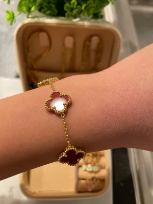 Guldarmband  - Armband i guldton med flera röda fyrklöverformade hängen. 💖