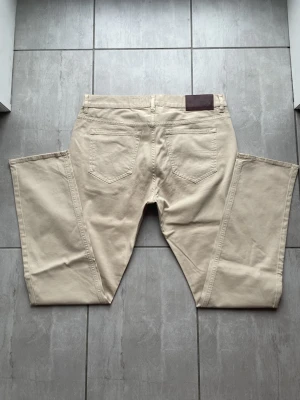 Chinos, Tiger of Sweden  - Snygga beige chinos från Lee med raka ben och klassisk femficksdesign. Tillverkade i mjukt bomullstyg som ger en skön känsla. Perfekta för dig som gillar en clean och stilren look. Diskret Lee-logga vid fickan och läderpatch bak i midjan. Nypris -:1199, vid frågor eller funderingar skriv gärna!