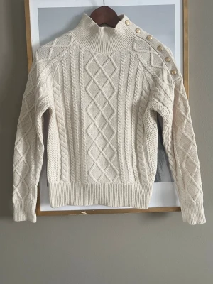 Vit kabelstickad tröja med guldknappar - Snygg kabelstickad tröja i offwhite säljer denna som är helt ny aldrig använt den ny pris 549kr