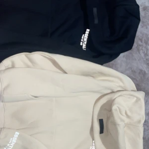 Essentials Fear of God hoodie svart & beige - Säljer två Essentials Fear of God-hoodies — en svart och en beige (bärsch). Båda är helt nya, aldrig använda och av A-kvalitet kopior (mycket bra material och passform, identiska med originalet). Mjuk insida, perfekt oversized fit och tydliga Essentials-tryck  Hoodiesarna är riktigt snygga och bekväma, men jag har bestämt mig för att sänka priset och sälja dem snabbt. Perfekt för dig som vill ha den ikoniska Essentials-looken utan att betala fullt pris. (Kan säljas enskilda)