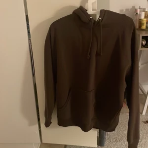 Brun hoodie från BikBok med huva - Mysig brun hoodie från BikBok i storlek M. Tröjan har en klassisk huva med snörning, stor magficka och långa ärmar. Materialet är mjukt och känns skönt mot huden, perfekt för chill dagar. Enkel och stilren design som funkar till många olika looks. Lite nopprig 