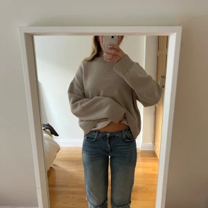 Lappade jeans Zara  - Säljer ett par blå jeans med låg midja och raka ben. Jeansen har en cool detalj med råa kanter och sömmar vid knäna som ger en unik look. Klassisk femficksmodell och tillverkade i jeansmaterial. Perfekt för dig som gillar en avslappnad och trendig stil.