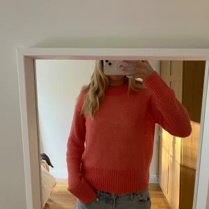 Stickad korallrosa tröja arket - Supermysig stickad tröja i en snygg korallrosa färg. Färgen visas bäst på tredje bilden. Modellen har rund hals, långa ärmar och breda ribbade muddar vid ärmslut och nederkant. 