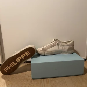 Vita sneakers från Philippe Model - Snygga vita sneakers från Philippe Model med en stilren design. Skorna har snörning och en diskret logga på sidan. Riktigt sköna stilrena och bra inför vintern. Lite slitage på hälarna. Fråga efter bild vid köp! Om ni vill!