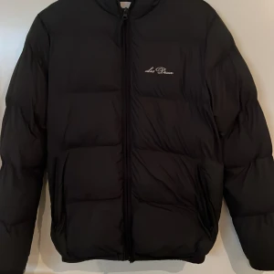 Svart pufferjacka från Les Deux XS - Säljer en svart pufferjacka från Les Deux i storlek XS. Jag har endast använt jackan i en vinter och den är i nyskick. Jackan har broderad logga på bröstet, dragkedja framtill och två fickor med dragkedja. Perfekt för kalla dagar och till de som vill ha en stilren jacka. Jackan passar perfekt till dig som är 176-180cm. Ställ gärna frågor om du har några. Mvh