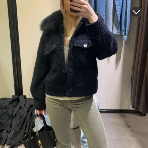 Kappa med päls  - Mysig svart teddyjacka med fluffig fuskpäls vid kragen. Jackan har stora knappar framtill, två bröstfickor med lock. Från Gina Young men passar absolut en xs/s storlek. Använd några gånger men väl omhändertagen så i mycket bra skick! Perfekt till vintern! 