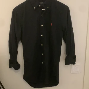 Mörk blå skjorta från Polo Ralph Lauren - Mörk blå polo Ralph lauren skjorta i XS fast passar S. På bilderna ser det ut som att den är svart fast egentligen mörk blå. 10/10 skick nästan aldrig använt. Pris går att diskuteras.
