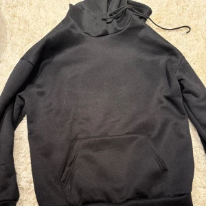 Svart hoodie med tryck och text - Svart hoodie med huva och känguruficka. På ryggen finns ett stort tryck med antik staty, rosa bakgrund och texten 'INTENSE FEELINGS' i vitt och rosa. Perfekt för dig som gillar streetstyle och coola prints.