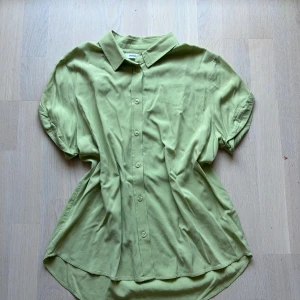 Ljusgrön skjorta från Samsøe Samsøe - Snygg ljusgrön skjorta från Samsøe Samsøe med korta ärmar och klassisk krage. Skjortan har knäppning framtill och är jättefin. Perfekt för dig som gillar stilrena plagg med en fräsch färg. Materialet känns mjukt och svalt mot huden. Använd få gånger. 