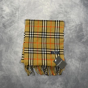Burberry Halsduk - Skick: 7/10 (Vintage), begagnad, inga defekter. | Vad som ingår: Endast halsduken. | Ordinarie pris: +- 4000 SEK / 400 €. | ​​OBS: Halsdukarna finns i samma färgsättning men kan skilja sig något i modell eller detaljer, beroende på tillverkningsår eller kollektion