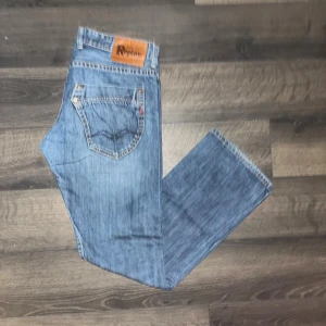 Replay jeans  - Säljer ett par klassiska blå jeans från Replay i rak passform. Jeansen har fem fickor, snygga slitningar och Replay-lapp bak i midjan. Tillverkade i bomull med autentisk denimkänsla. Midja 42cm, längd 102cm. JAG SKICKAR INGA FLER BILDER NÄR JAG BÄR JEANSEN:) OBS se defekt på sista bilden. S2