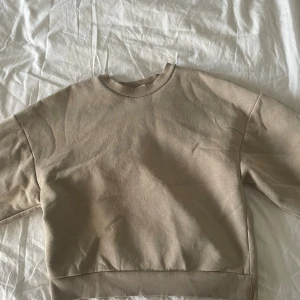 Beige sweatshirt från Gina Tricot XS - En enkel och snygg beige sweatshirt från Gina Tricot, basically basics-kollektionen. Tröjan har rund hals, ribbade muddar vid hals, ärmslut och nederkant samt lång ärm. Perfekt för chill dagar och enkel att matcha med jeans eller leggings.