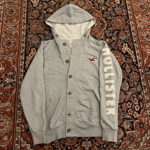 Vintage hollister hoodie:Cardigan! - Riktigt fet vintage Hollister cardigan/hoodie! Dessa har blivit extremt eftertraktade senaste så därav priset! Bra skick inga konstigheter!  Mått: Bredd: 49cm Längd: 64cm