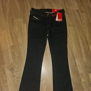 Bootcut Jeans Diesel - Snygga jeans från Diesel med klassisk bootcut passform och kontrasterande gula sömmar. Modellen har fem fickor, knapp och dragkedja fram. Helt oanvända med lappar kvar. W27 L32