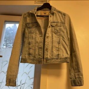 Ljusblå jeansjacka från Zara - Snygg ljusblå jeansjacka från Zara med klassisk passform. Jackan har två bröstfickor med lock och knappar, samt knappar framtill och vid ärmslut. Perfekt för dig som vill ha en tidlös och cool look till vardags.