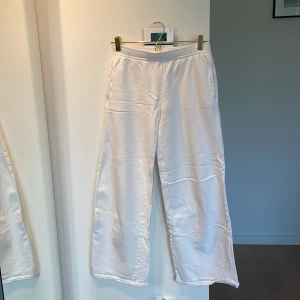 Vita mjukisbyxor | Kappahl - Vita mjukisbyxor från Kappahl i storlek 164. Byxorna har resår i midjan, raka och vida ben samt sidofickor. 100% bomull. Observera bild 2! Det finns en fläck fram, men inget som syns direkt dock. 